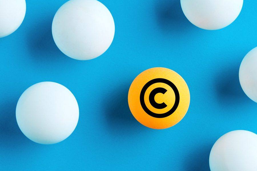 Orangefarbene Kugel mit Copyright-Symbol zwischen weißen Kugeln auf blauem Hintergrund